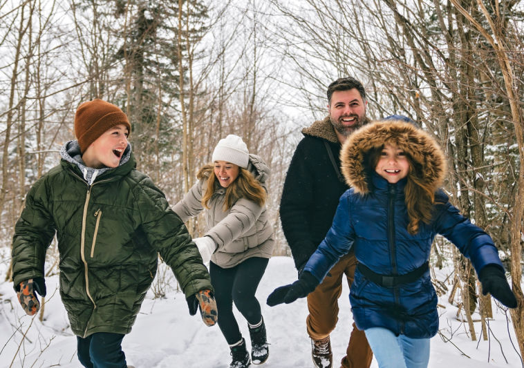 A Dad and three kids running outside In the winter  in Manotick